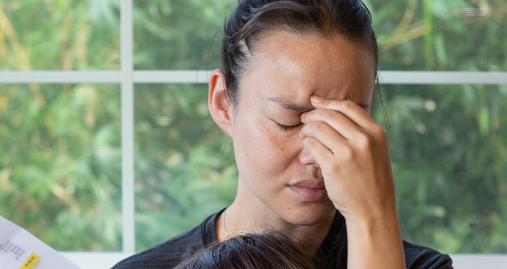 A woman holding her face in pain after reading a bill