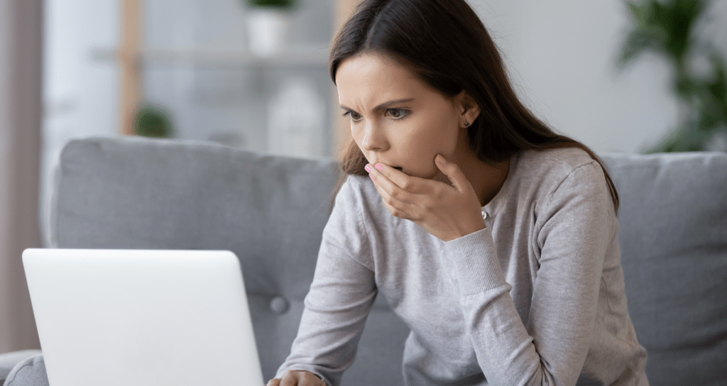 A woman looking at a laptop with concern.