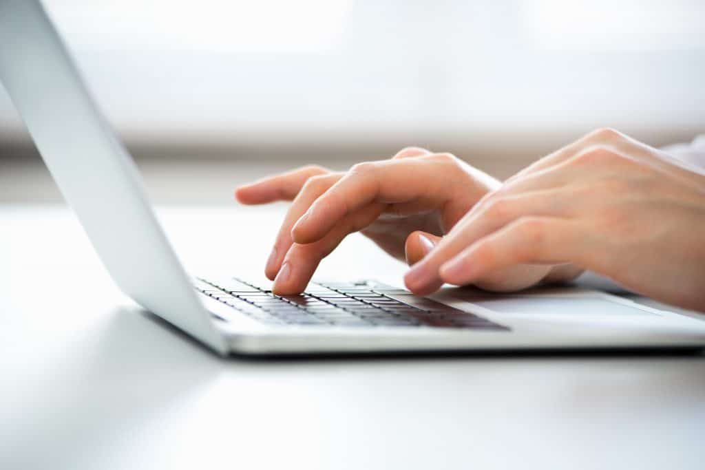 Close up of hands typing on a laptop.