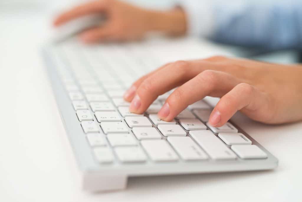 A close up of a persons hands typing on a keyboard